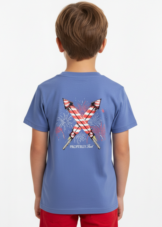 A blue graphic t-shirt with a pattern of crossed firecrackers and the text ' Properly Tied ' on the front.