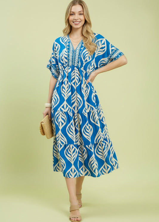 Woman wearing a blue and white patterned dress on a light green background with 'Mumee Exclusive' branding.