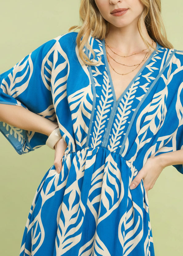 Woman wearing a blue and white patterned dress against a light green background
