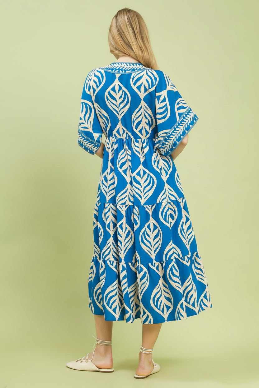 Woman wearing a blue and white patterned dress on a light green background with 'UMgee Exclusive' branding.