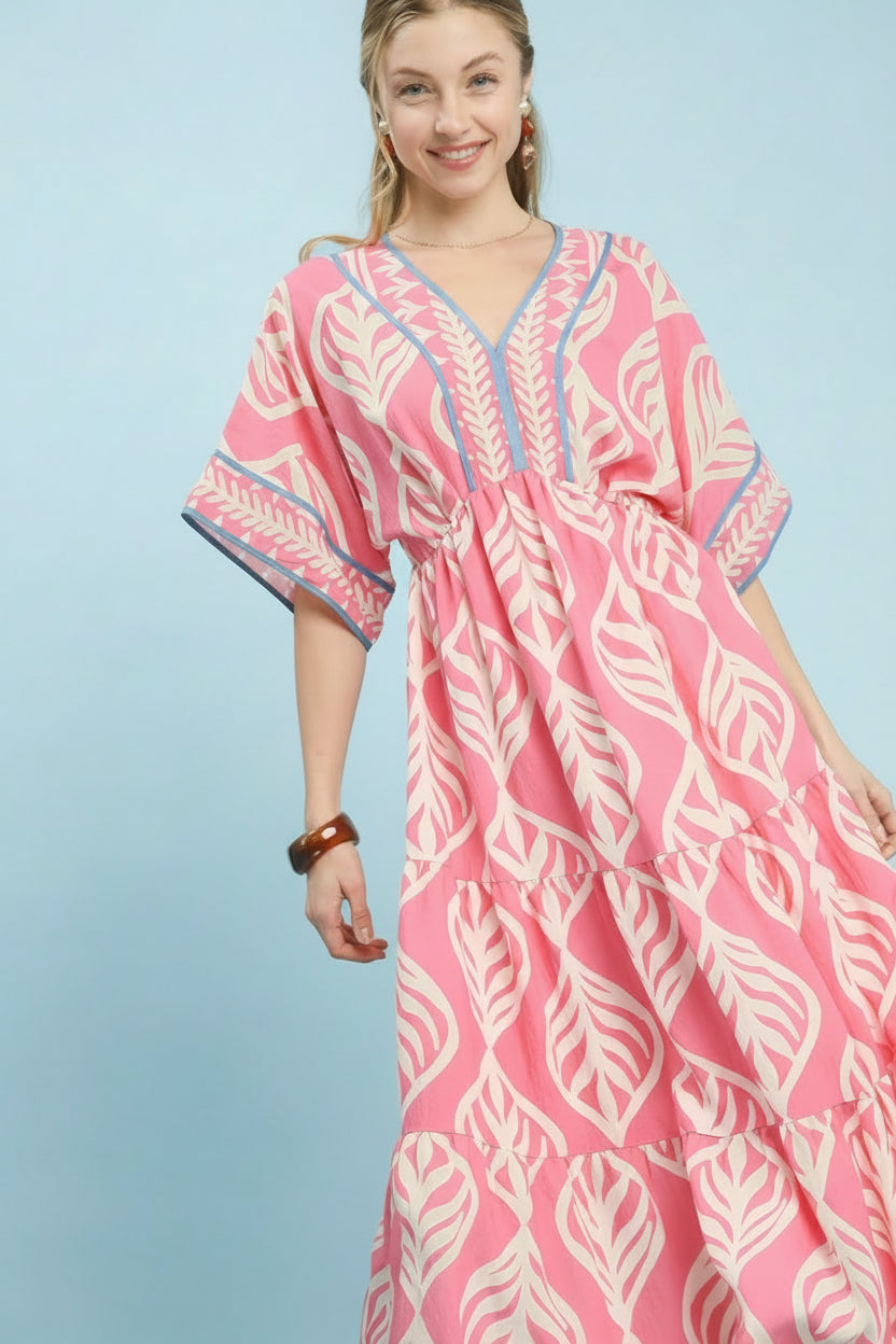Woman wearing a pink and white patterned dress with 'UMgee Exclusive' branding on a light blue background.