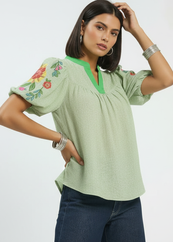 Woman wearing a green blouse with floral embroidery on a white background