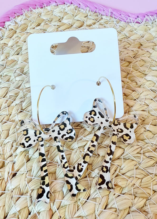 Leopard print earrings on a branded card against a woven mat background