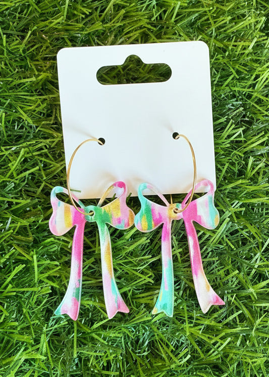Colorful earrings on a branded card against a grass background