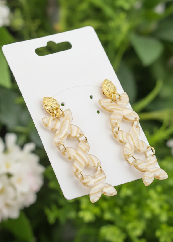 Gold leaf earrings on a display card with a scenic background