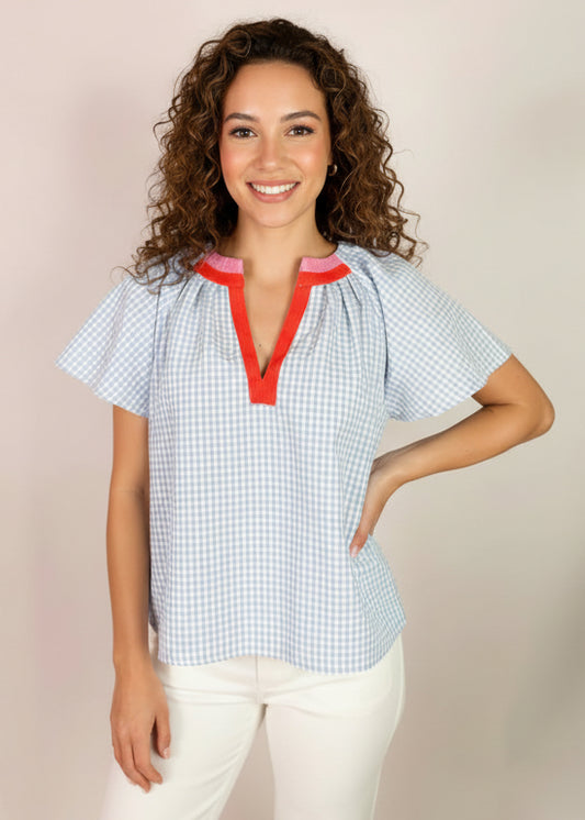 Woman wearing a blue checkered top with red accents on a beige background