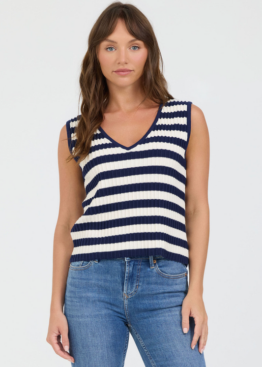 Woman wearing a navy and white striped sleeveless top with blue jeans on a white background