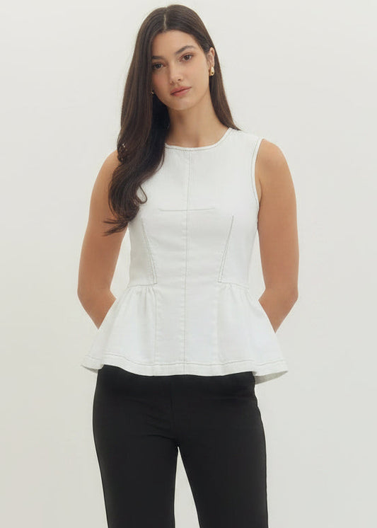 Woman wearing a white sleeveless top and white pants with floral cutouts on a plain background