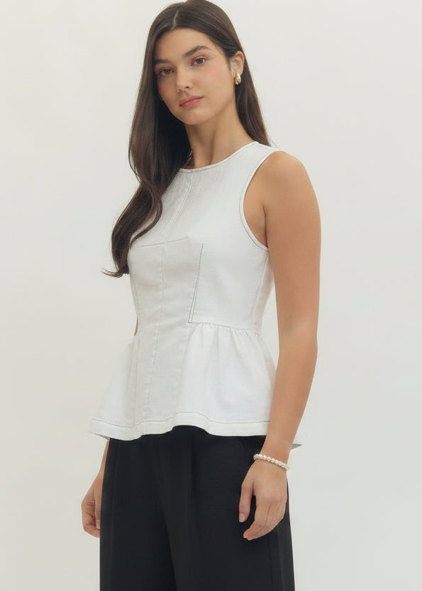 Woman wearing a white sleeveless top and pants on a plain background