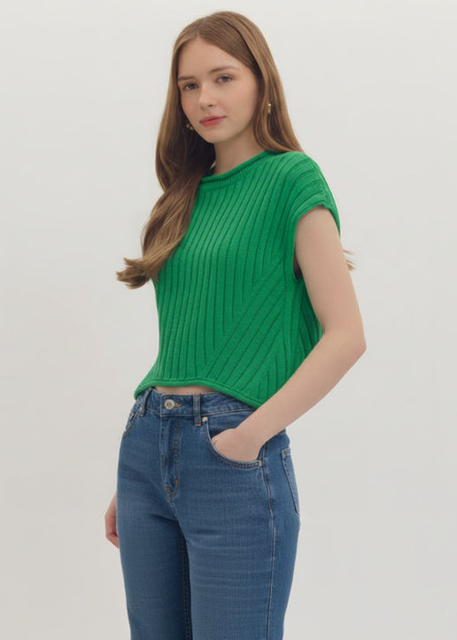 Woman wearing a green ribbed top and white shorts on a light gray background