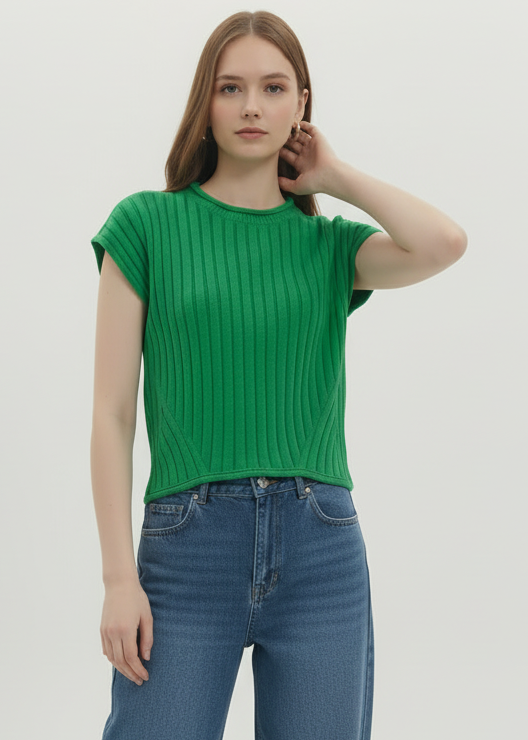 Woman wearing a green ribbed top and blue jeans on a plain background