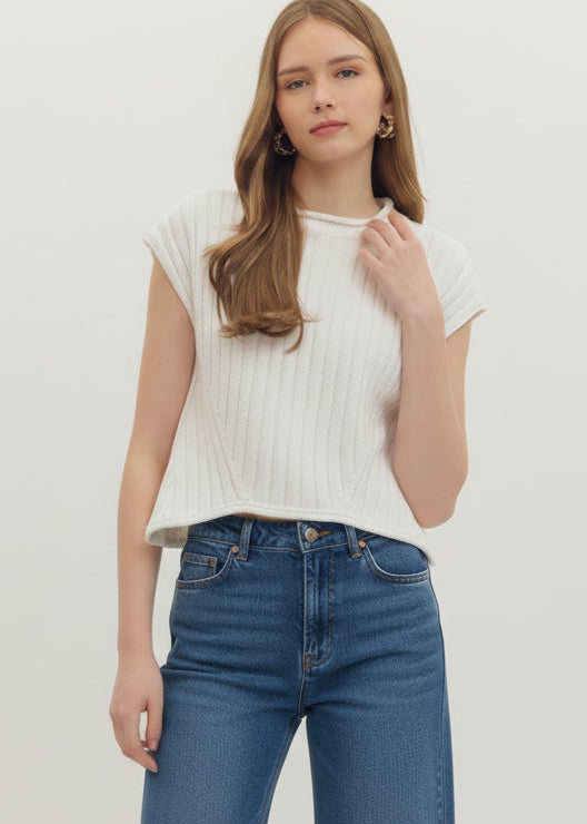 Woman wearing a white ribbed top and shorts on a plain background