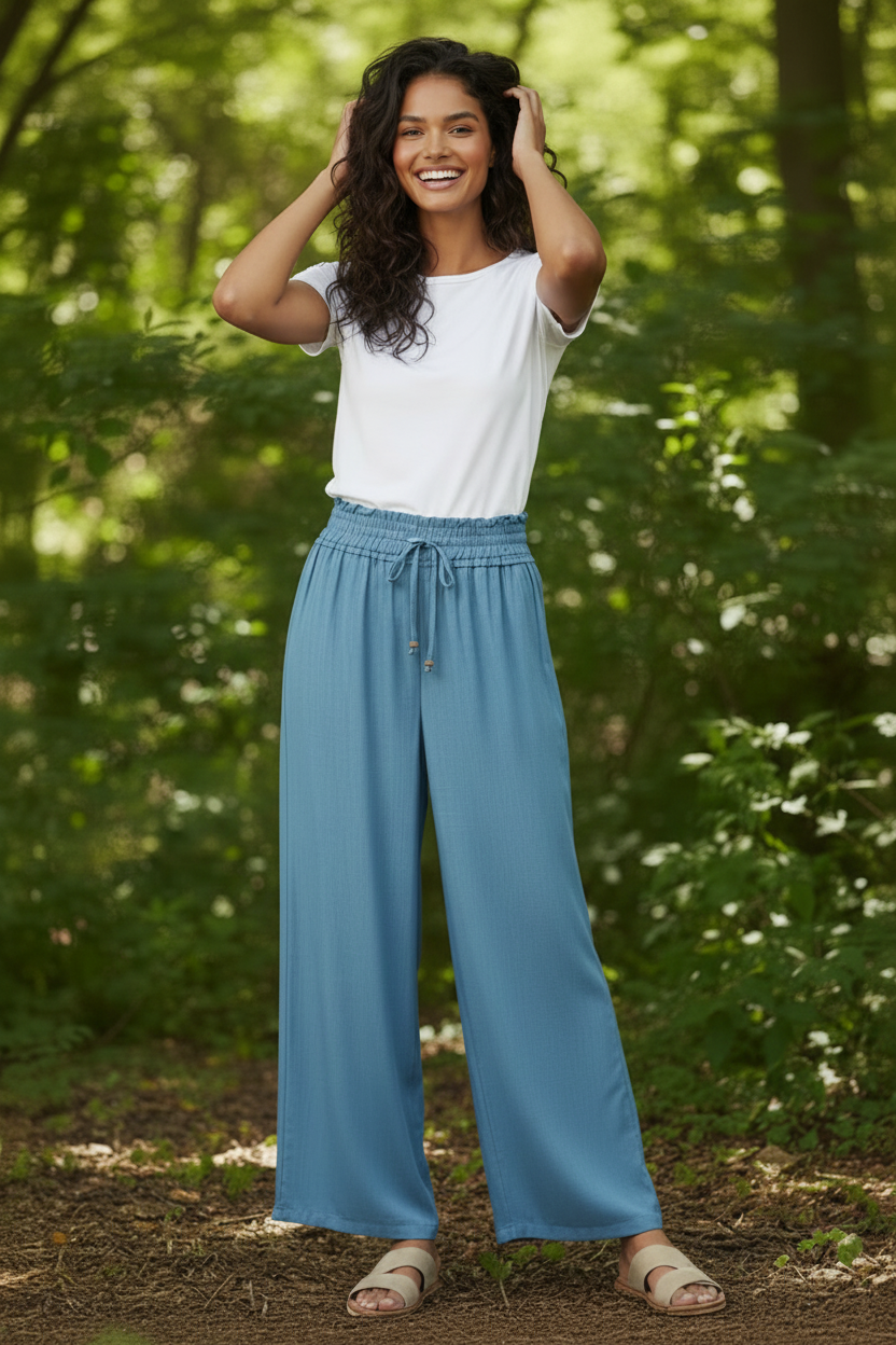 Woman wearing a white top and blue pants standing in a forest