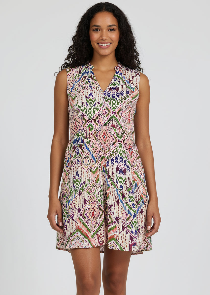 Woman wearing a sleeveless, patterned dress against a plain background