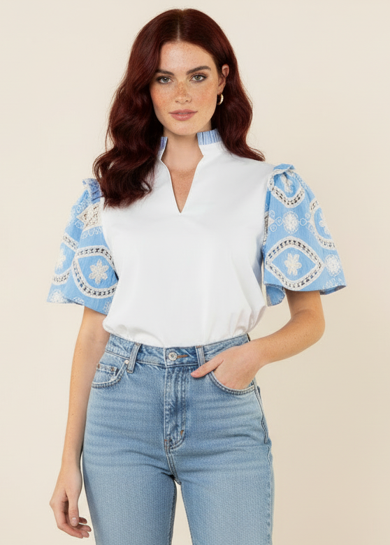Woman wearing a white blouse with blue embroidered sleeves and a denim skirt on a white background