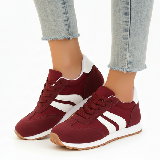 Red sneakers with white stripes worn with light blue jeans on a white background