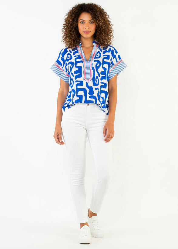 Woman wearing a blue patterned top and white shorts on a white background