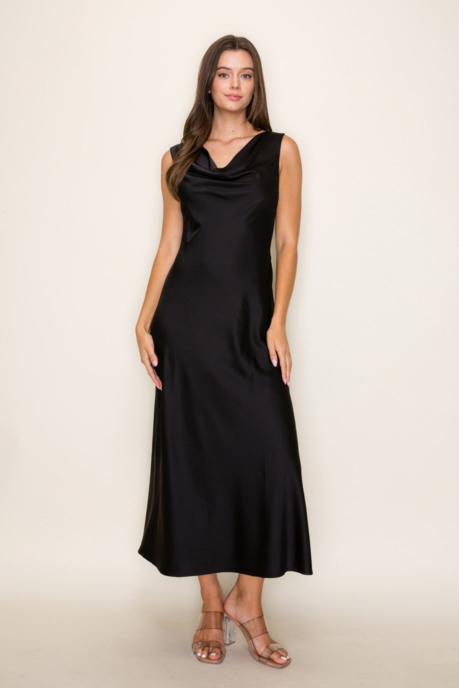Woman wearing a black sleeveless dress against a beige background