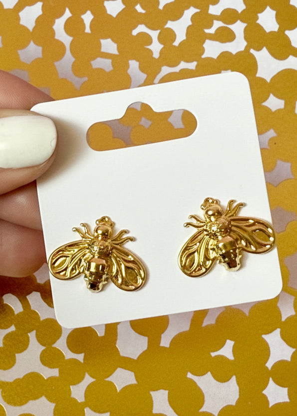 Gold bee-shaped earrings on a Sandy Rizzo branded card against a yellow patterned background.