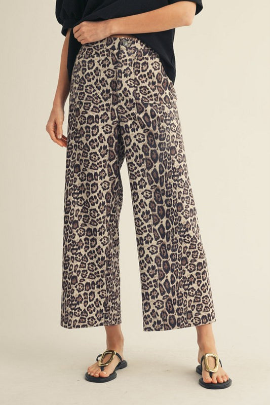 Person wearing leopard print pants on a beige background