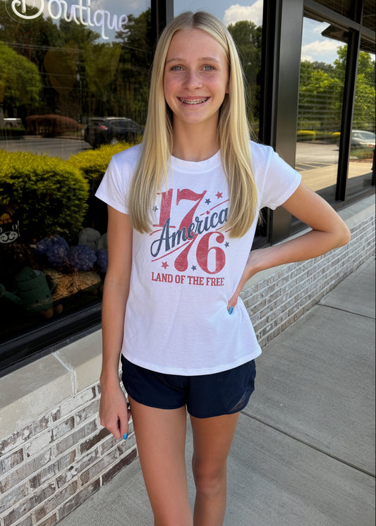 Person wearing a white t-shirt with red text, standing in front of a store entrance.