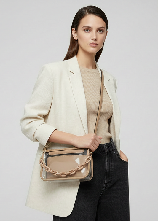 A taupe and clear crossbody bag with a chain strap and vegan leather trim.