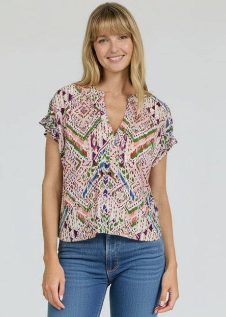Woman wearing a colorful patterned blouse and blue jeans on a plain background