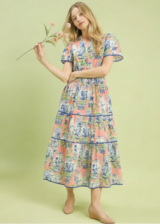 Woman wearing a floral dress holding a flower against a light green background