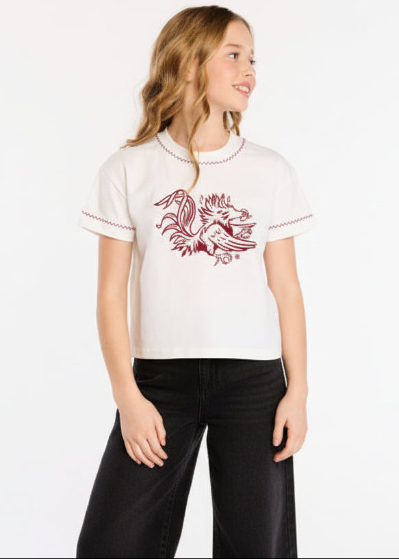 Woman wearing a white blouse with red floral design on a plain background