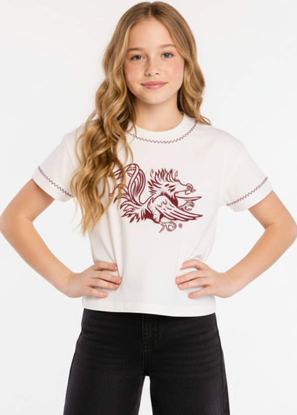 Young girl wearing a white t-shirt with a red graphic design on a plain background