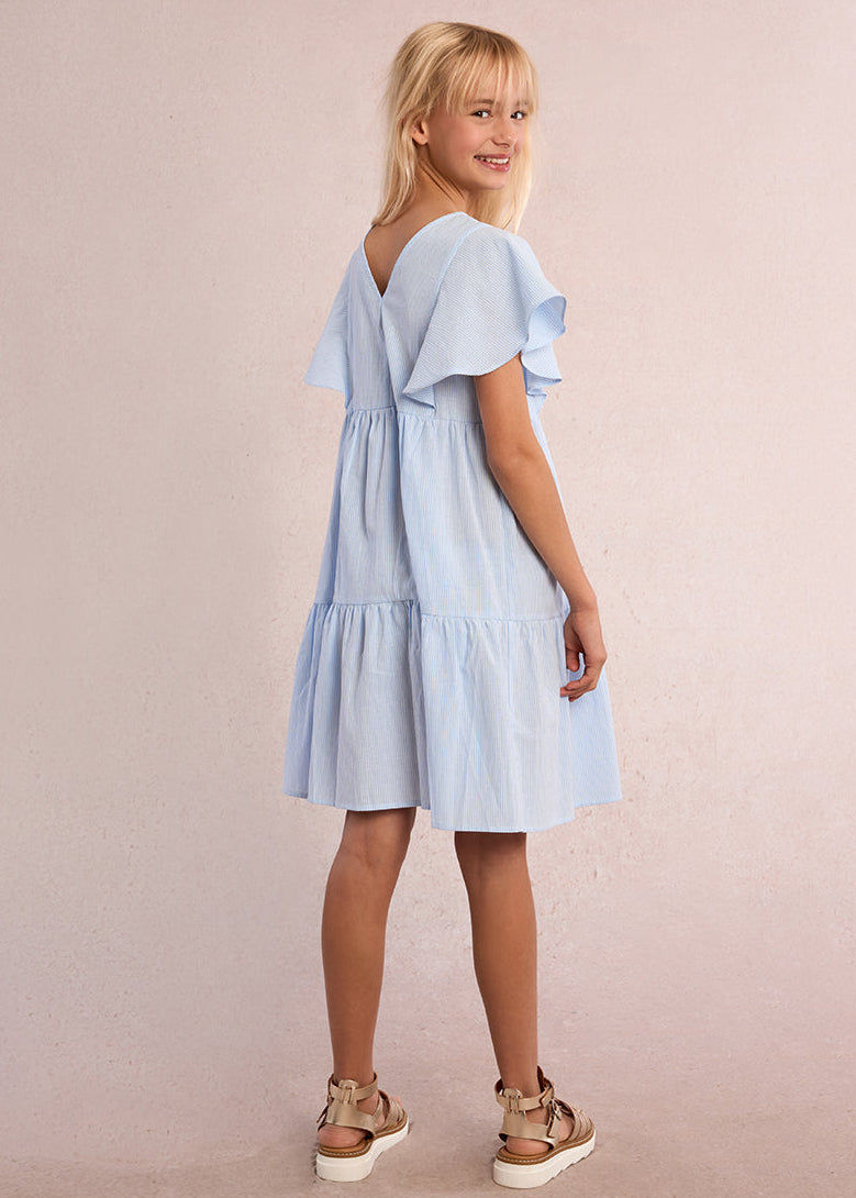 Young girl wearing a light blue dress against a plain background