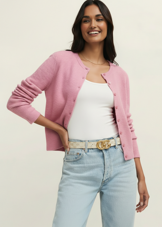 Woman wearing a pink cardigan, white top, and light blue jeans on a beige background