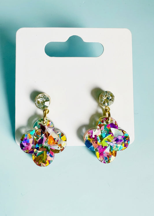 Colorful earrings on a display card with 'SR' branding against a light blue background