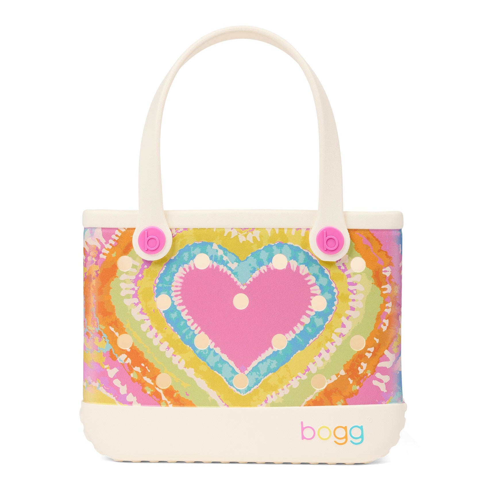A Bogg brand
 bag with a colorful tie-dye heart pattern on the front, featuring cream-colored handles and base, and pink decorative buttons on the sides.