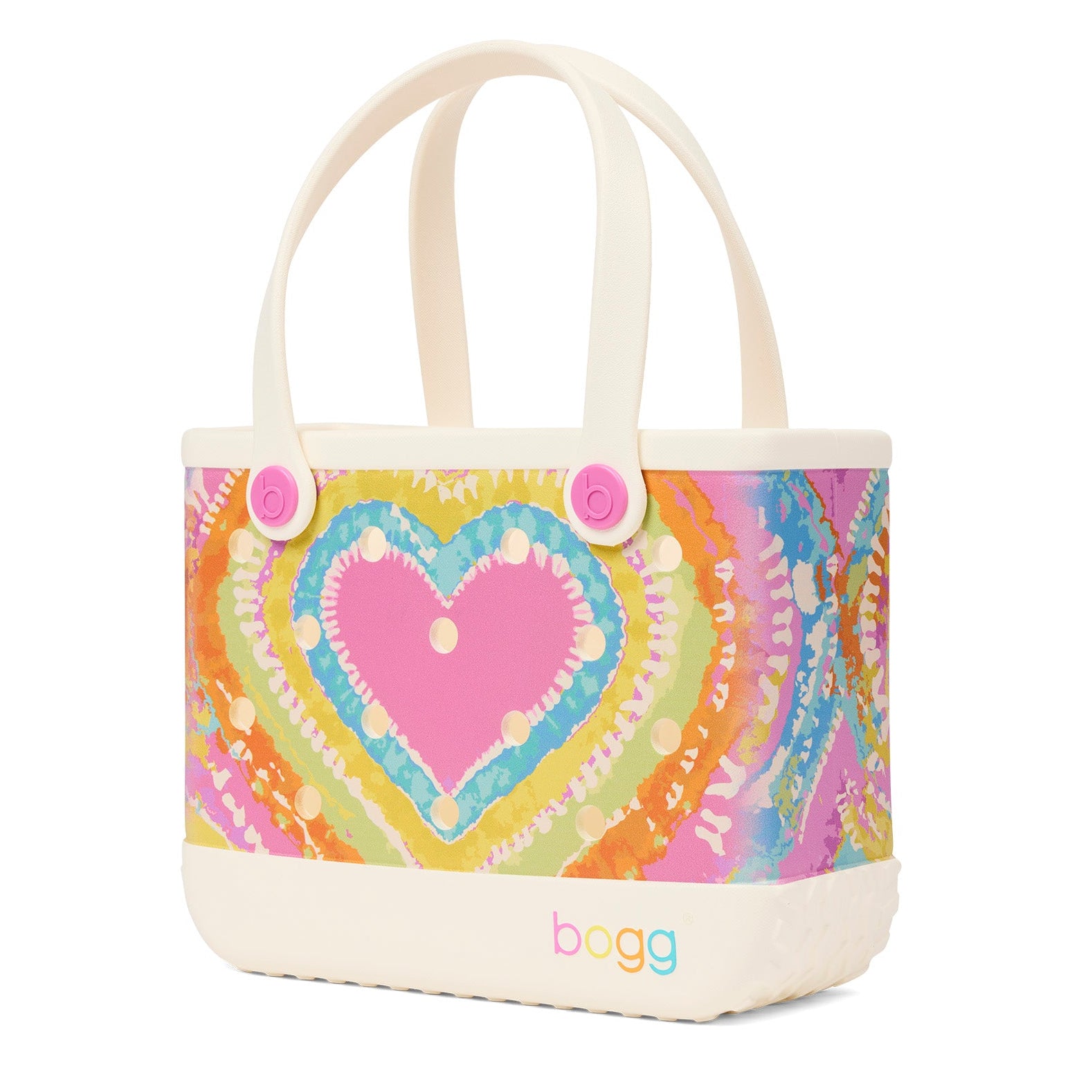 A Bogg brand canvas tote bag with cream-colored handles and base, featuring a colorful tie-dye style heart pattern in pink, orange, yellow, green, and blue on the front.