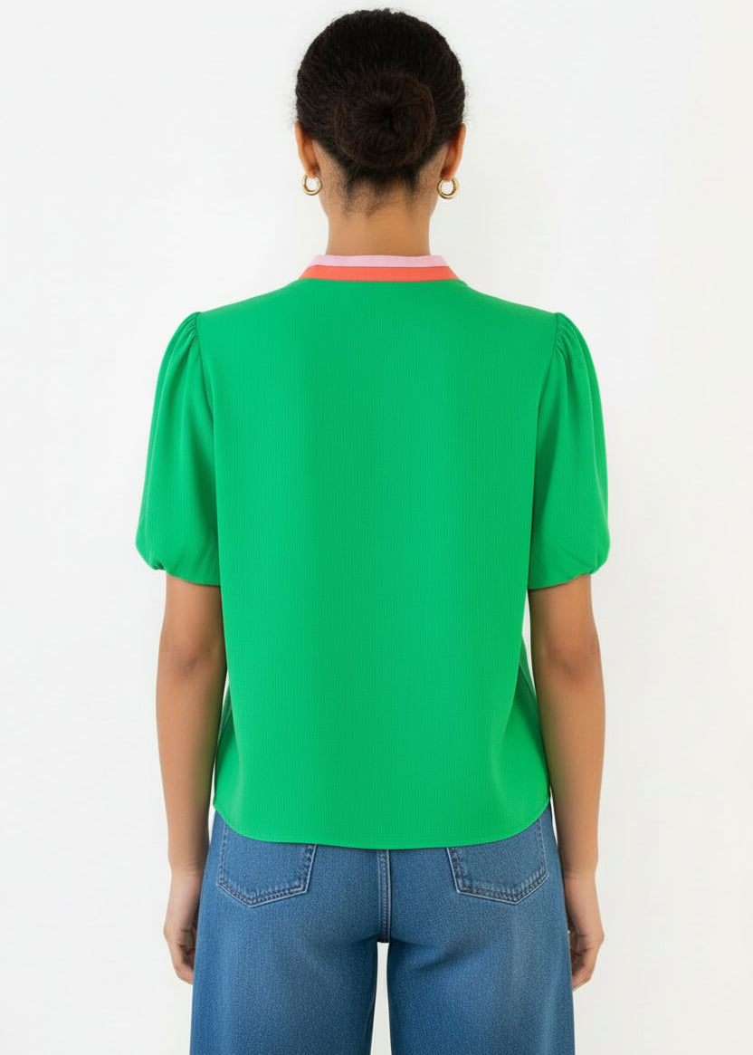 Woman wearing a green jumpsuit with red accents on a white background