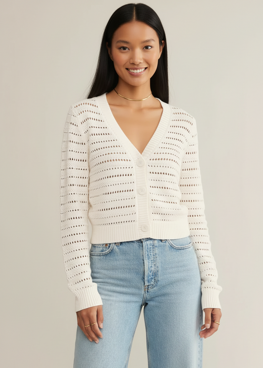 Woman wearing a white lace top and light blue jeans against a plain background