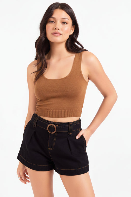 A woman modeling a brown ribbed tank top with decorative studs along the neckline, paired with black denim shorts featuring a matching belt with a round gold-tone buckle, against a plain white studio background.