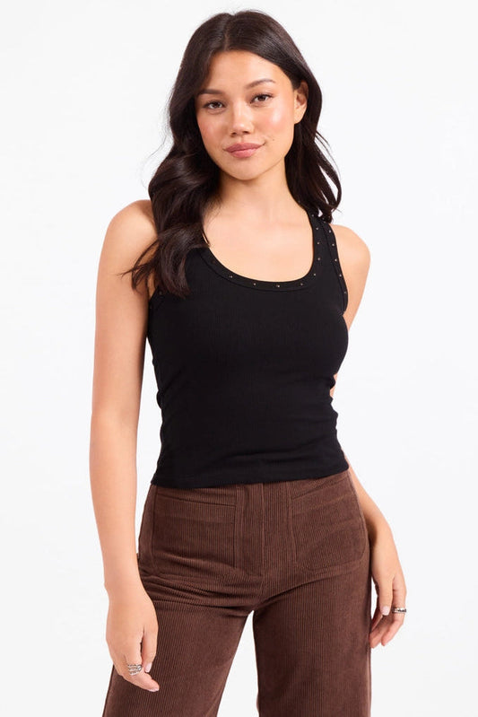 Woman wearing a black tank top and brown pants on a white background