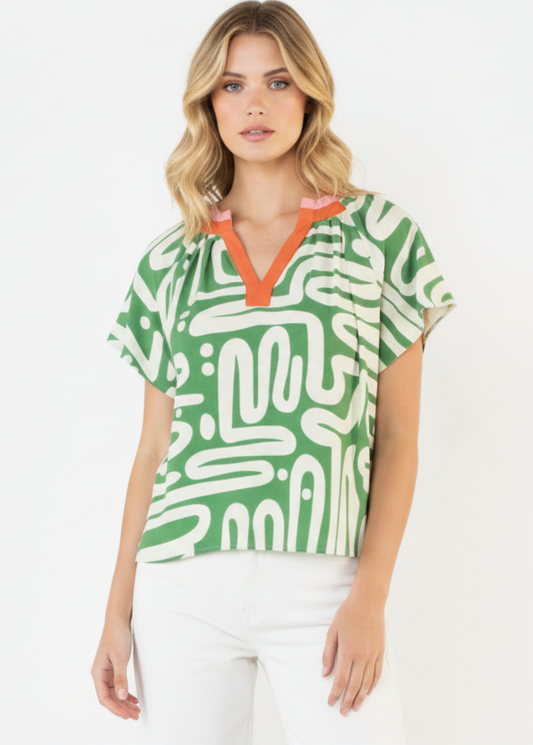 Woman wearing a green patterned top with orange accents on a white background