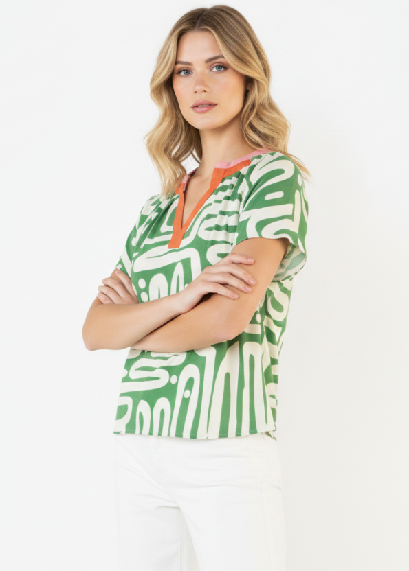 Woman wearing a green patterned top with orange accents on a white background