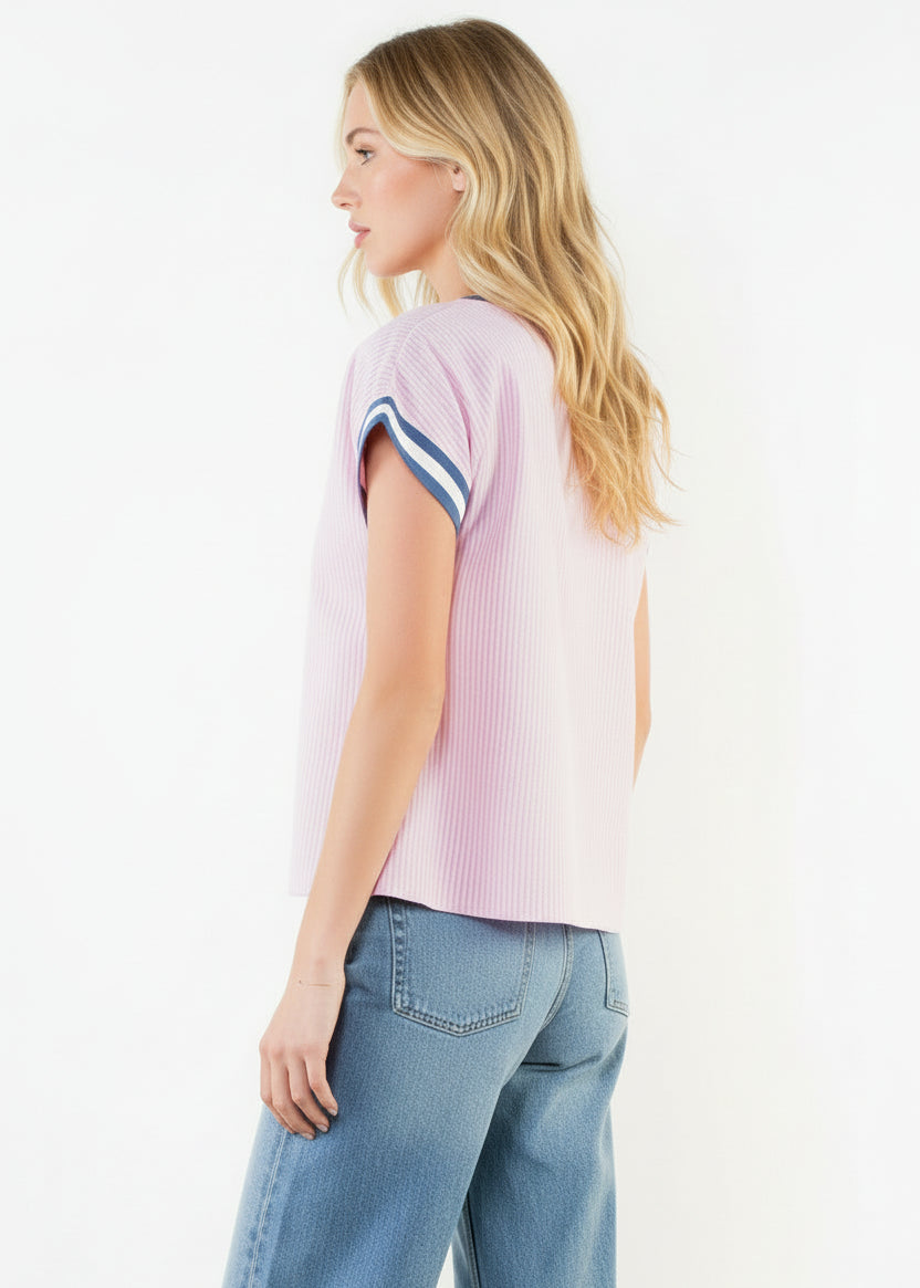 Woman wearing a pink ribbed sweater with white shorts on a white background