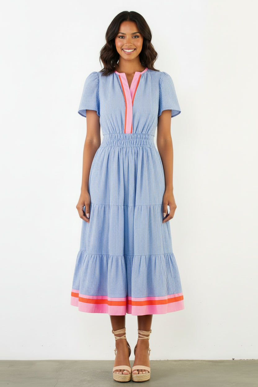 Woman wearing a blue dress with pink accents against a white background