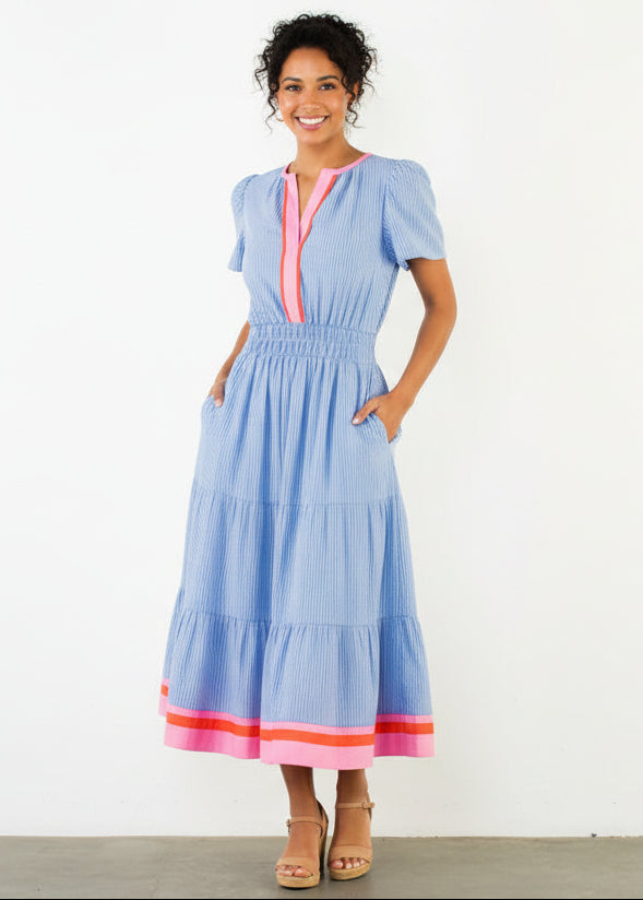 Woman wearing a blue dress with pink accents against a white background