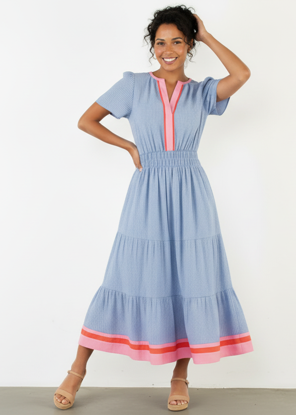 Woman wearing a blue dress with pink accents against a white background
