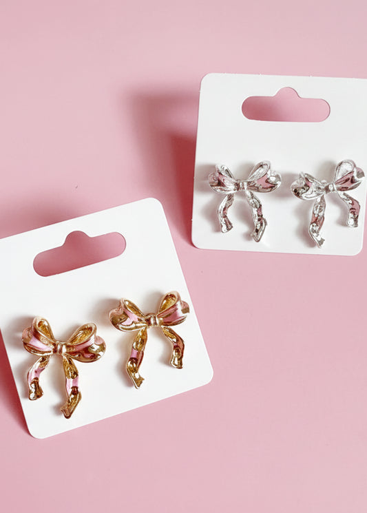Bow-shaped earrings on white cards with a pink background