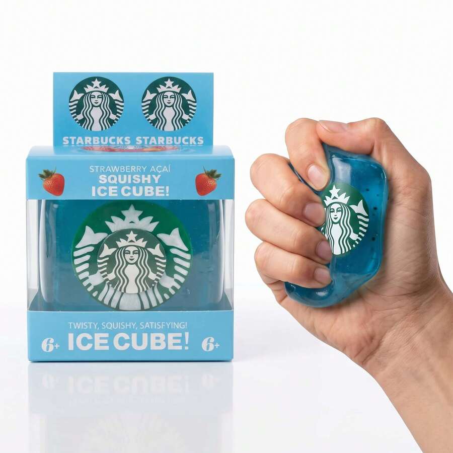 A hand squeezes a translucent blue Starbucks ice cube toy next to its light blue retail box on a clean white background.