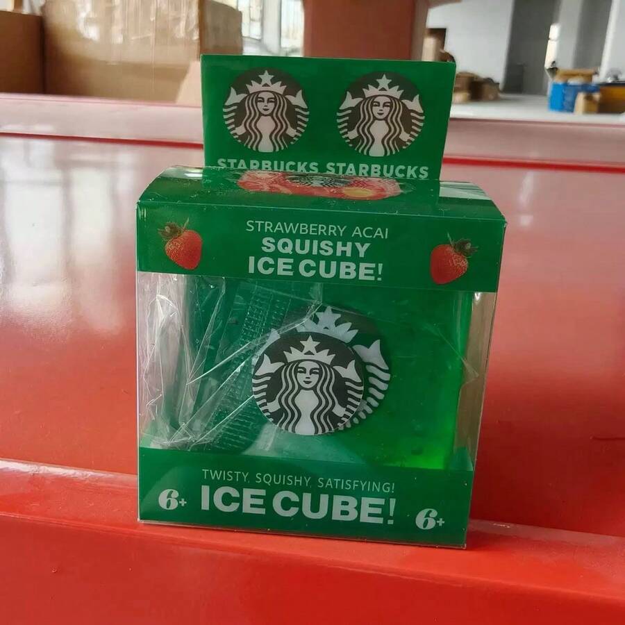 Starbucks Strawberry Acai Squishy Ice Cube toy in its green packaging, featuring the green Starbucks logo and text on a red surface.