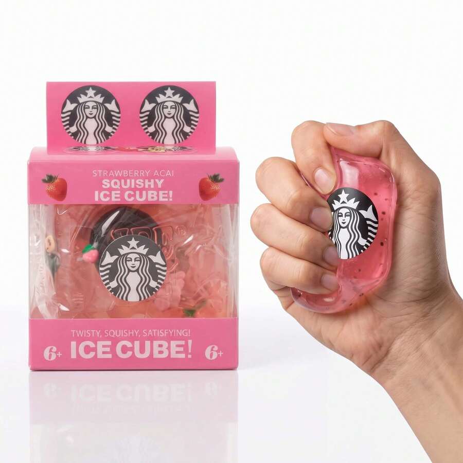 A hand holds a pink, squishy Starbucks Ice Cube toy next to its retail packaging box on a clean white background.