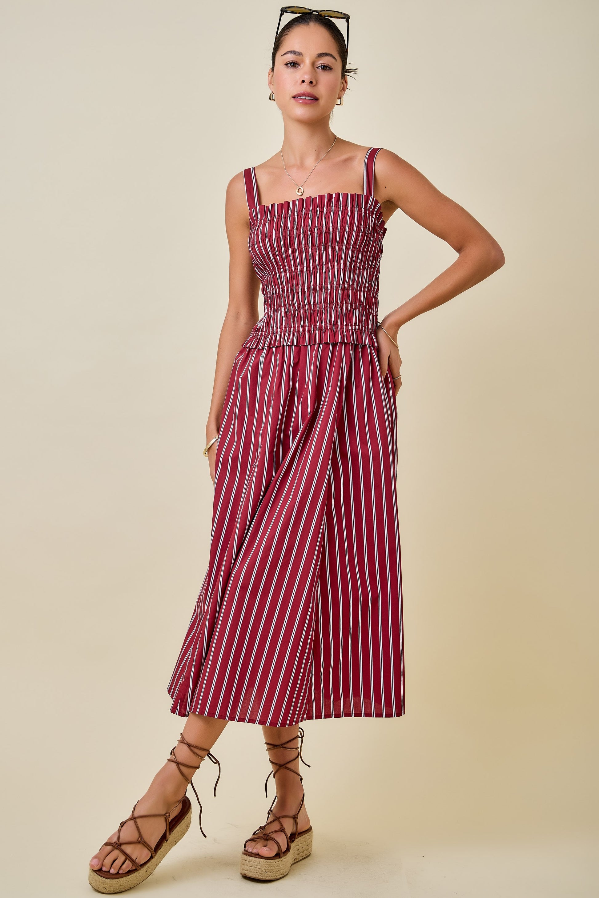 Woman wearing a red and white striped dress on a beige background